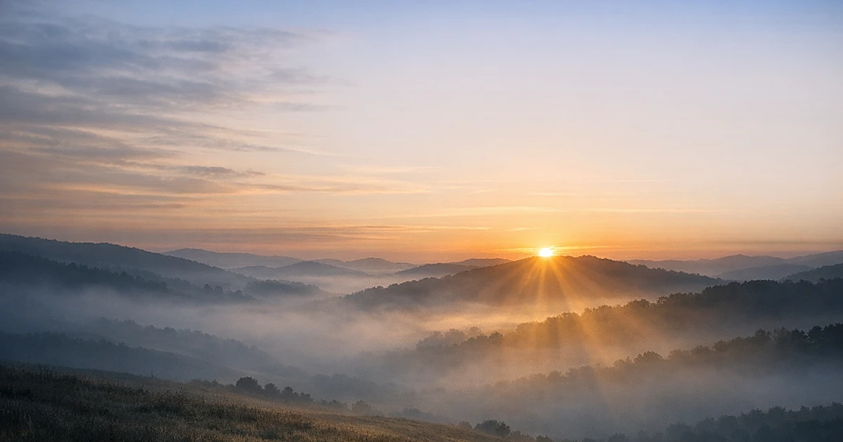 Golden sunrise breaking through mist over peaceful hills, representing hope and positive resolution