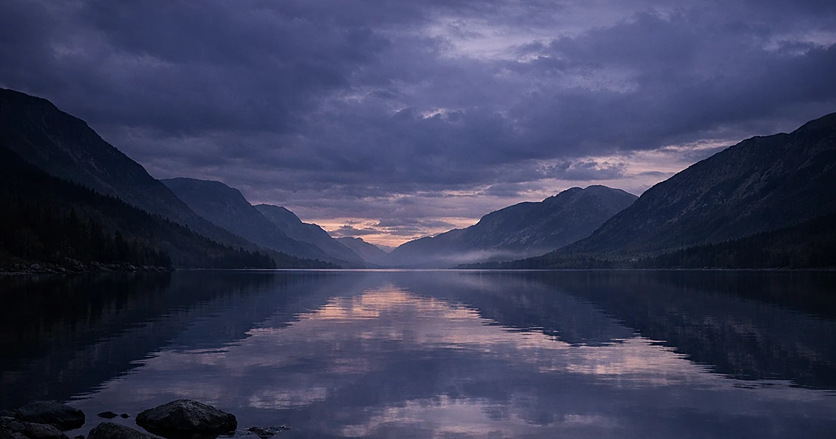 Peaceful twilight scene with still lake waters reflecting grey and purple clouds at dusk